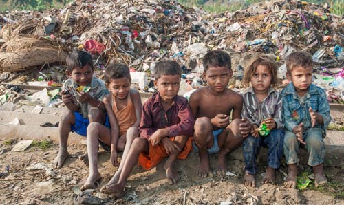 A small group of children gathered near a pile of waste